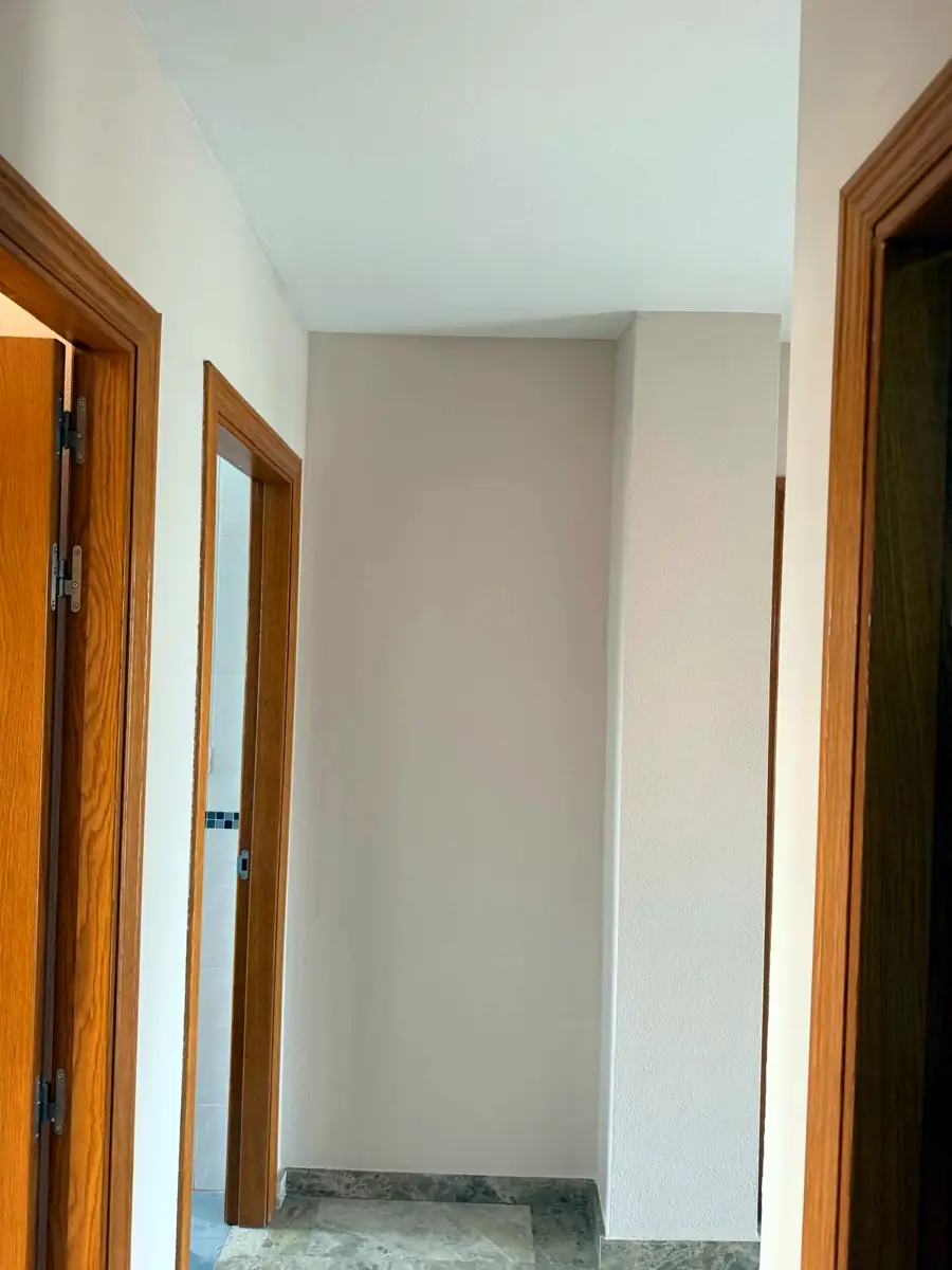 Pasillo de vivienda recién pintado con acabado liso en blanco